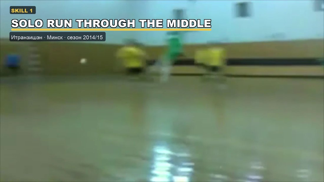 Futsal match on a wooden indoor court, a player in green carrying the ball through the middle against a team in yellow.