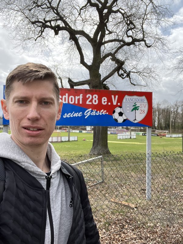 Anton Abyzov standing in front of the SV Rangsdorf 28 e.V. club sign at the entrance to the ground.
