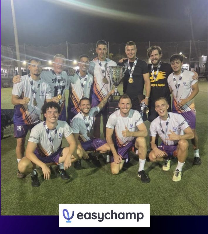 The EasyChamp FC squad with the cup and their medals on a floodlit pitch after the Superliga 8v8 title.