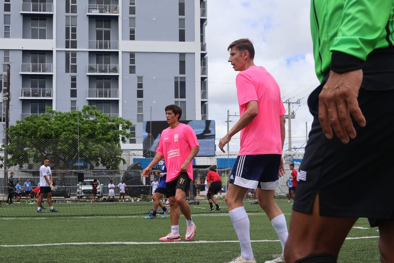 Anton Abyzov in a pink kit shielding the ball from an opponent on a Miami pitch.