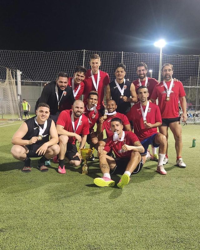 The Team Patagonia squad gathered around the cup on a floodlit pitch at night.