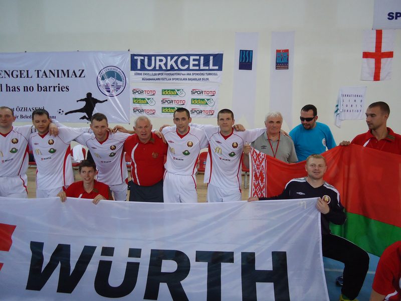 A wider view of the Belarus squad behind the sponsor banner in the Kayseri hall, with tournament signage on the wall.