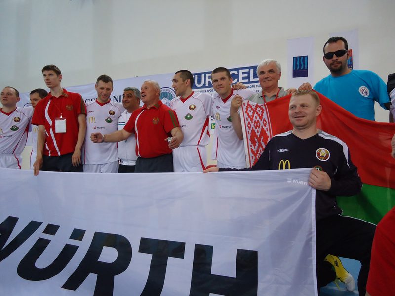 The Belarus squad standing behind a sponsor banner with the national flag held up behind them in the Kayseri hall.