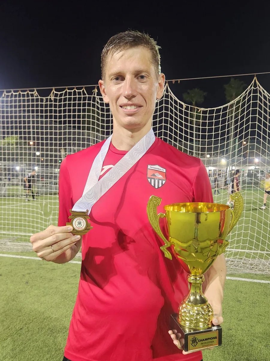 Anton Abyzov in the red Patagonia FC shirt holding the 5v5 champions cup in one hand and a winner&rsquo;s medal in the other.