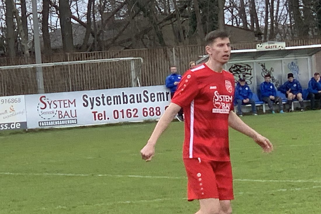 Anton Abyzov in the red SV Rangsdorf 28 kit close to the touchline, the away bench behind him.