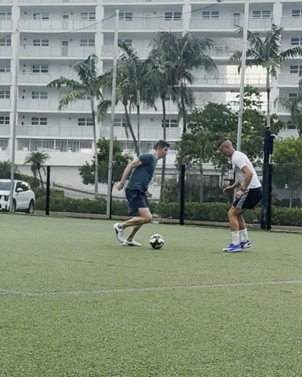 Anton Abyzov driving at a defender shoulder to shoulder during a one-on-one drill on Miami turf.